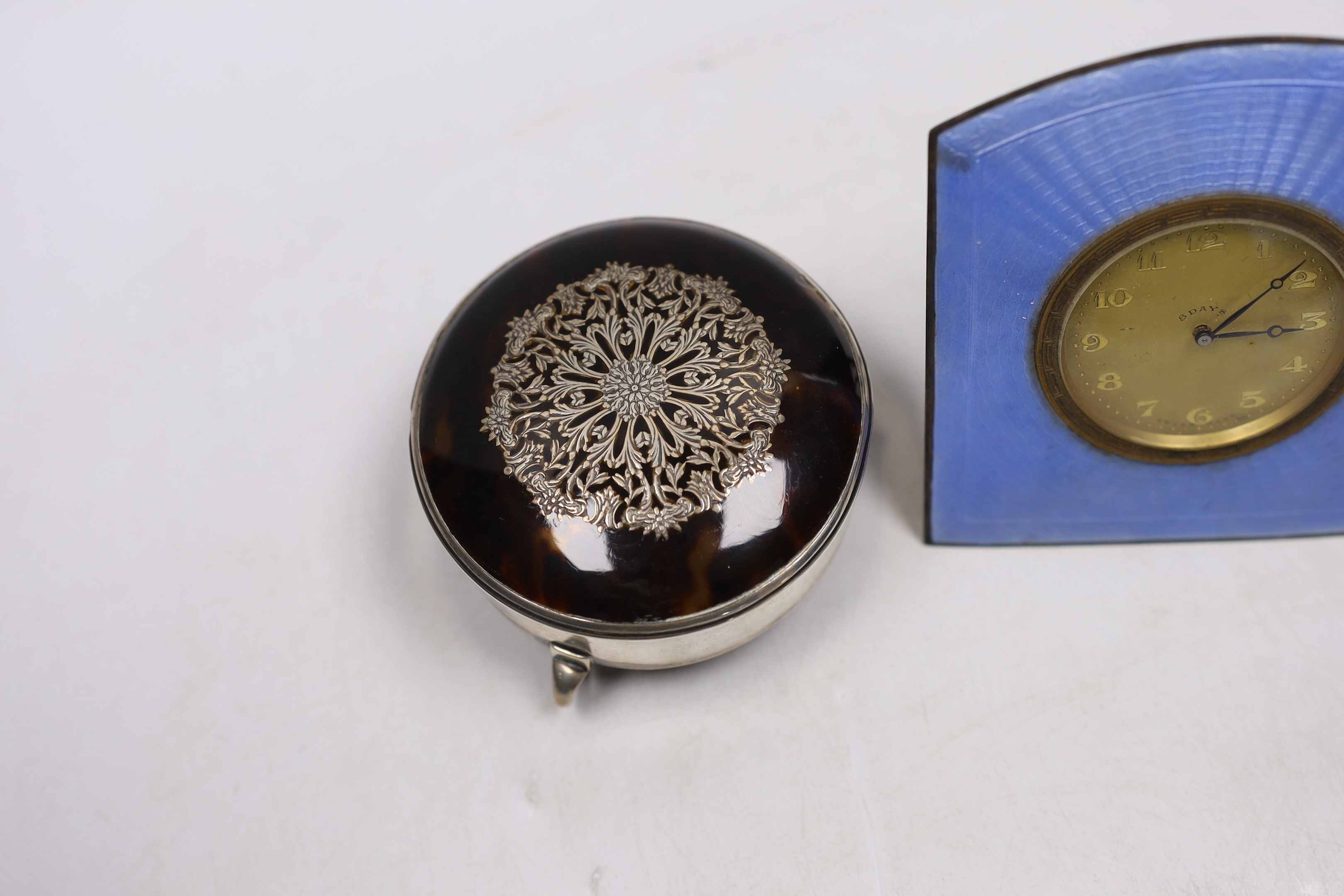 A George V silver and tortoiseshell pique mounted trinket box, by William Comyns, London, 1913, 79mm and an enamelled bedside timepiece.